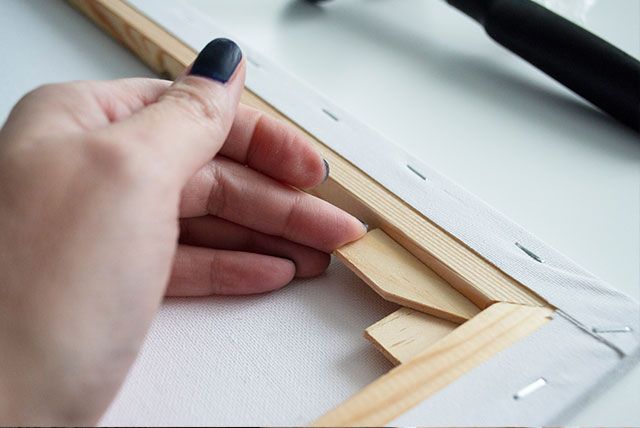 A person assembling a canvas frame with stretcher bars